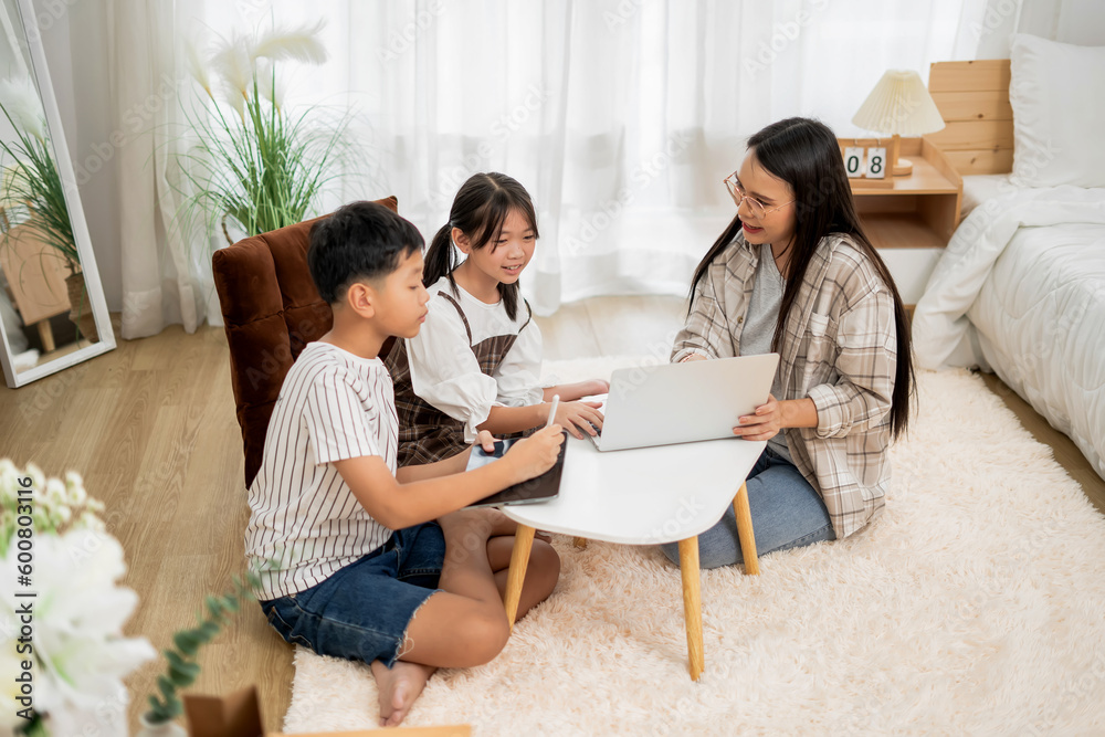 Asian mother teaching children online learning on laptop in white room of home happy smile Asian mother teaching children online learning on laptop in white room of home happy smile