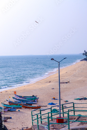 the boats standing on the mud near an ocean with light pole and clear sky
