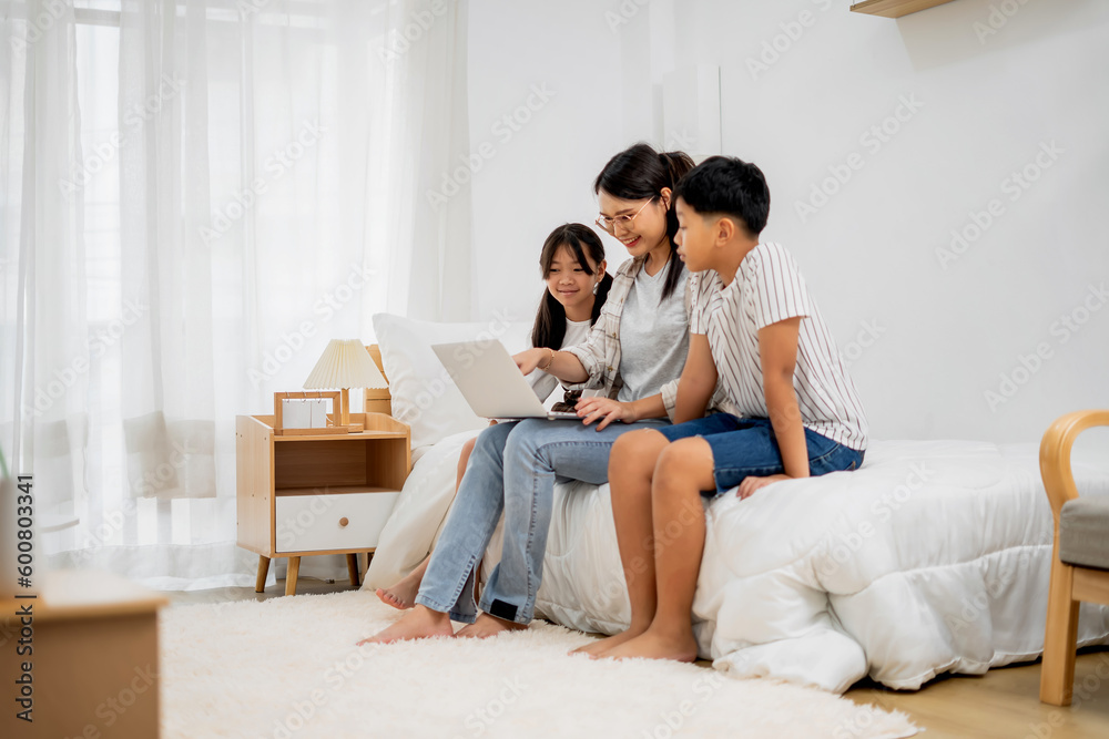 Asian Mother Teaching Children Online Learning on Laptop in white room of Home Happy Smile Asian Mother Teaching Children Online Learning on Laptop in white room of Home Happy Smile