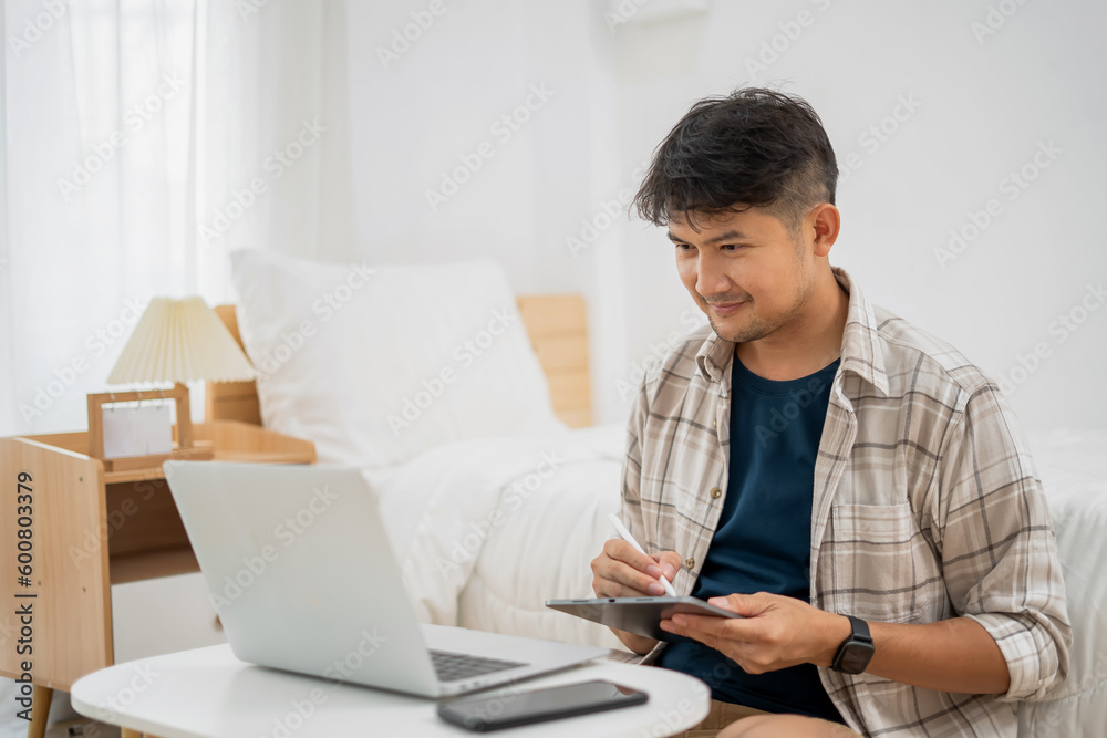 A Young Man Working on his Laptop Asian Male Freelance Businessman using Laptop Computer to Work Online Searching for Technical Information on the Internet sitting at a Desk. A Young Man Working on his Laptop Asian Male Freelance Businessman using Laptop Computer to Work Online Searching for Technical Information on the Internet sitting at a Desk.