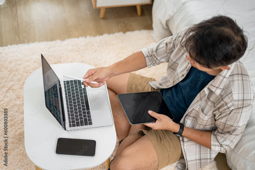 Naklejka premium A Young Man Working on his Laptop Asian Male Freelance Businessman using Laptop Computer to Work Online Searching for Technical Information on the Internet sitting at a Desk.