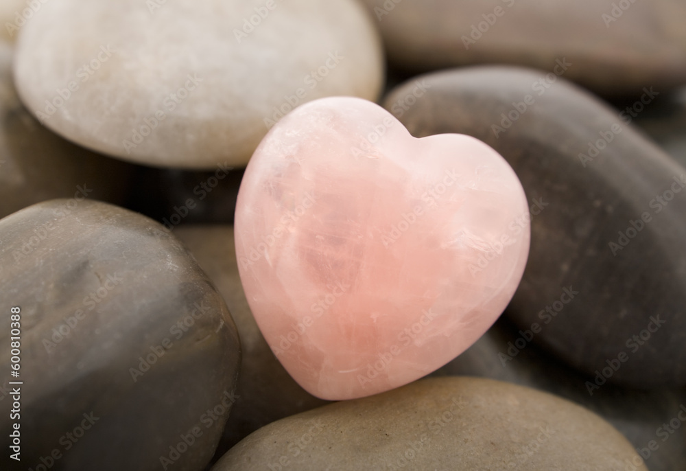 Fototapeta premium Rose quartz heart on pebbles