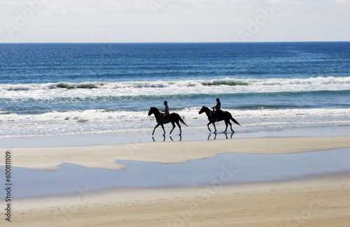 People on the beach riding horses.