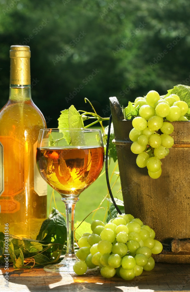 White wine with bottle and grapes on a rustic table
