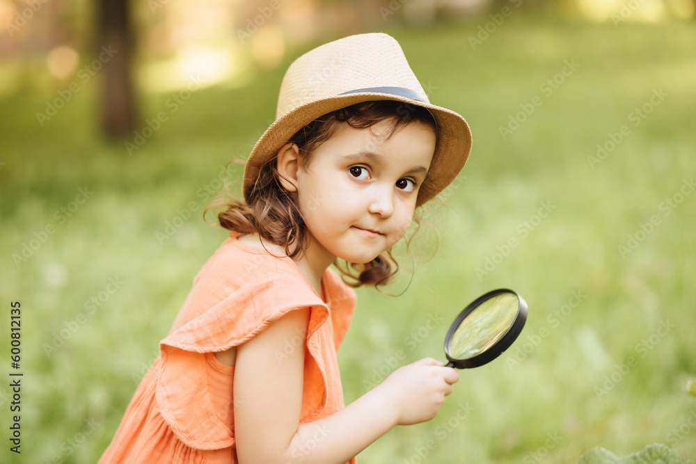 Caucasian little cute girl exploring nature environment with a magnifying glass loupe Caucasian little cute girl exploring nature environment with a magnifying glass loupe