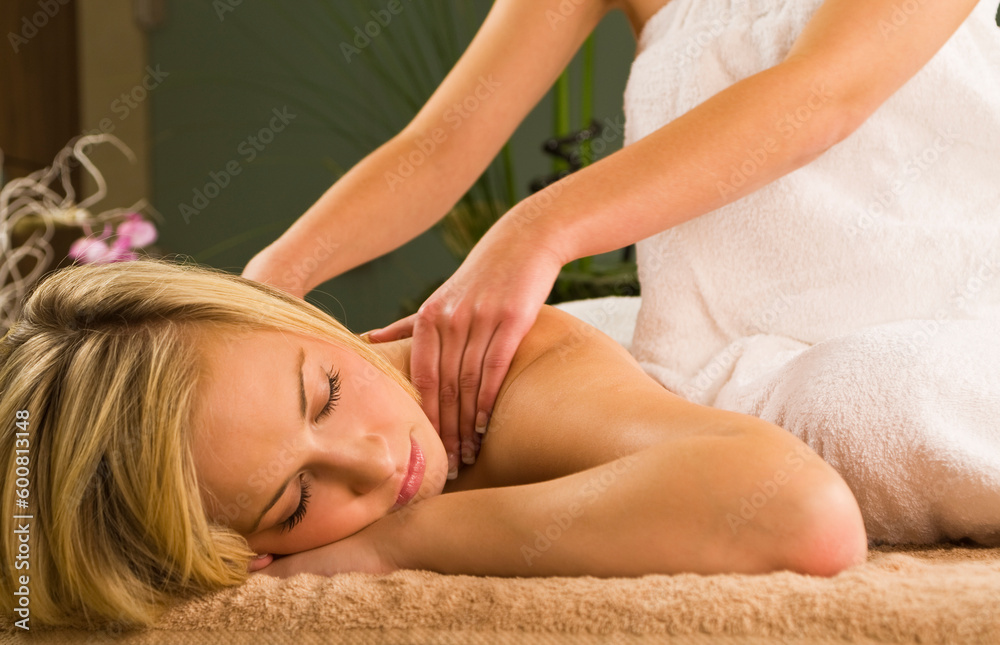 Fototapeta premium A young woman relaxing at a health spa while having a massage