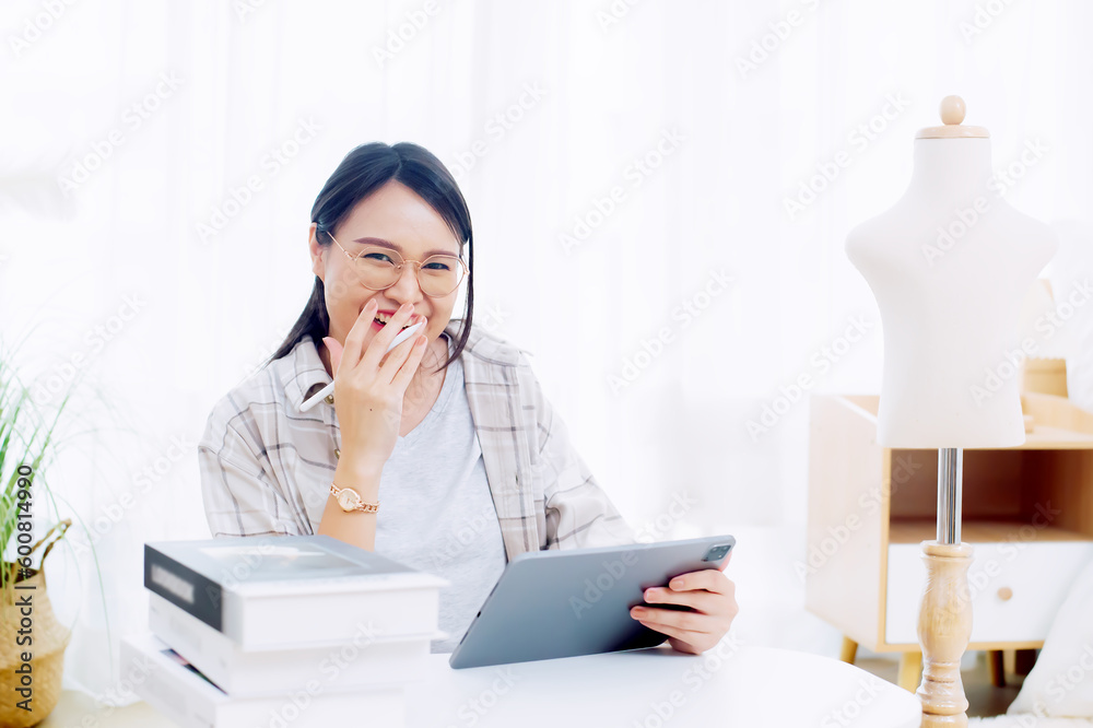 Asian woman enjoying designing clothes which is a job that she happily loves Asian woman enjoying designing clothes which is a job that she happily loves