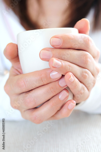 Hands of a mature woman holding a cup