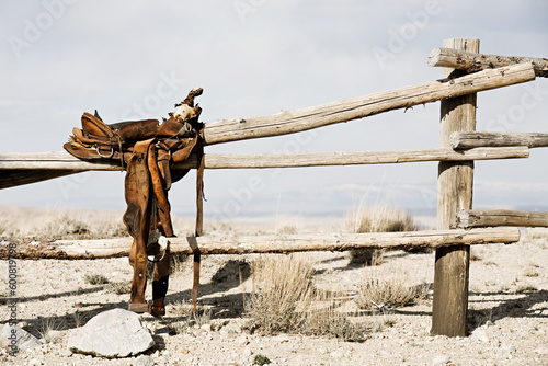 Fotografía ranch scene - saddle on rural fence, vintage worn saddle in the dry and barren c