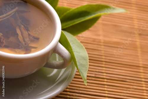 a cup of green tea with freh leaves on the bamboo tray photo