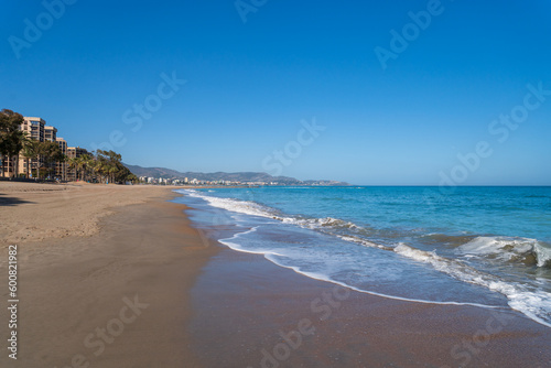 A wide sandy beach of the Mediterranean Sea in Spain. A sunny warm spring day.