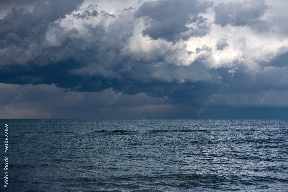Landscape photo of dark grey thunderstorm clouds over the sea