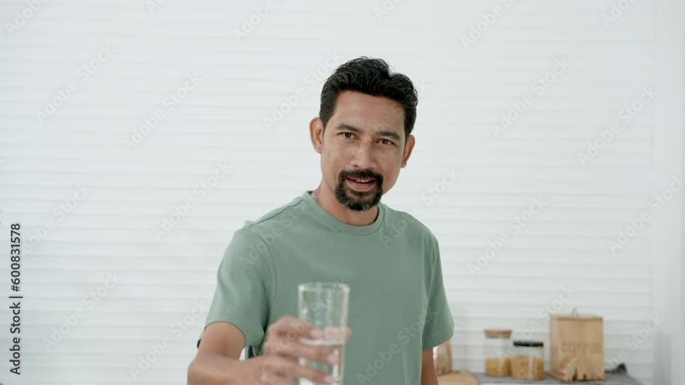 Slow motion, Asian man wearing comfortable pajamas on holiday morning, this man handed out glass water for drinking clean water, use words invite everyone drink lot clean water, good for health. Slow motion, Asian man wearing comfortable pajamas on holiday morning, this man handed out glass water for drinking clean water, use words invite everyone drink lot clean water, good for health.