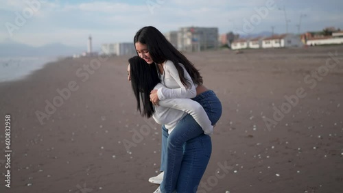 mother and daughter having fun piggyback ride on the beach in La Serena