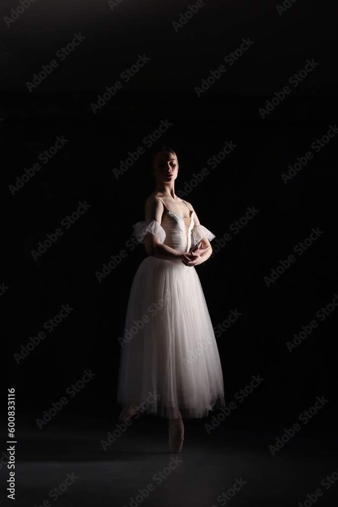 Professional ballerina dancing ballet.Ballerina in a white dress and pointe shoes. Dark background. Beautiful female body. Professional ballerina dancing ballet.Ballerina in a white dress and pointe shoes. Dark background. Beautiful female body.