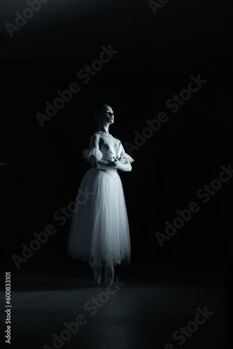 Professional ballerina dancing ballet.Professional ballerina dancing ballet.Ballerina in a white dress and pointe shoes. Dark background. Black and white