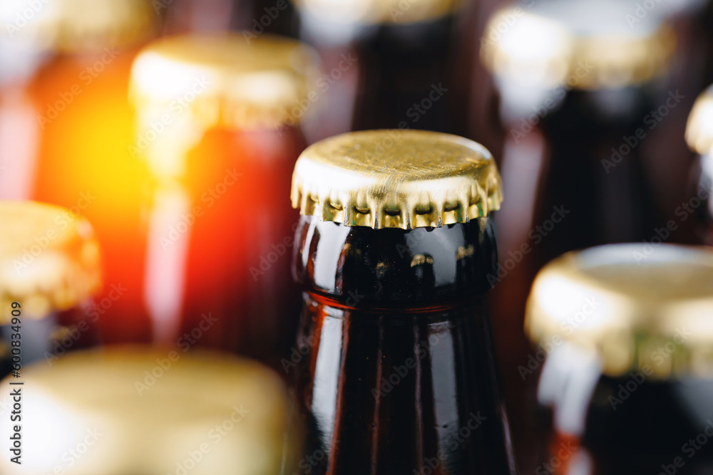 Glass bottles of beer on dark background with sun light. Brewery plant production line