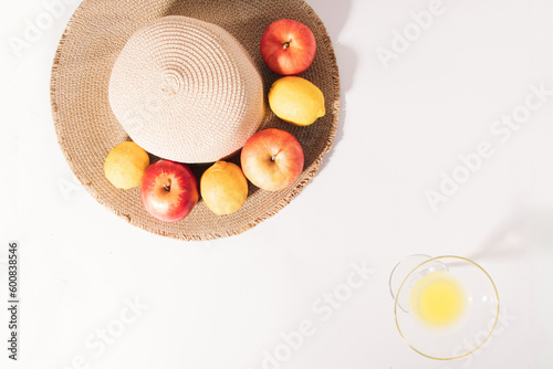 Summer tropical composition made of fresh organic fruit  a summer beach hat  and a cocktail glass full of juice against a white background. Minimal nature flat lay.