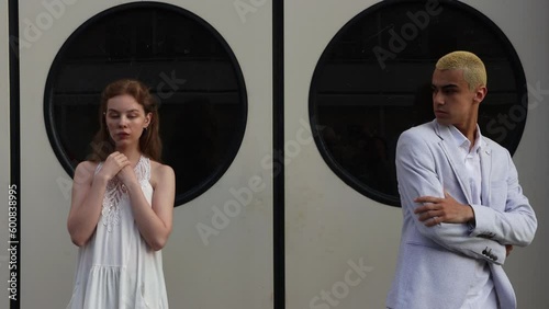 Young girl and guy are standing against background of black round windows of portholes. 4K Resolution