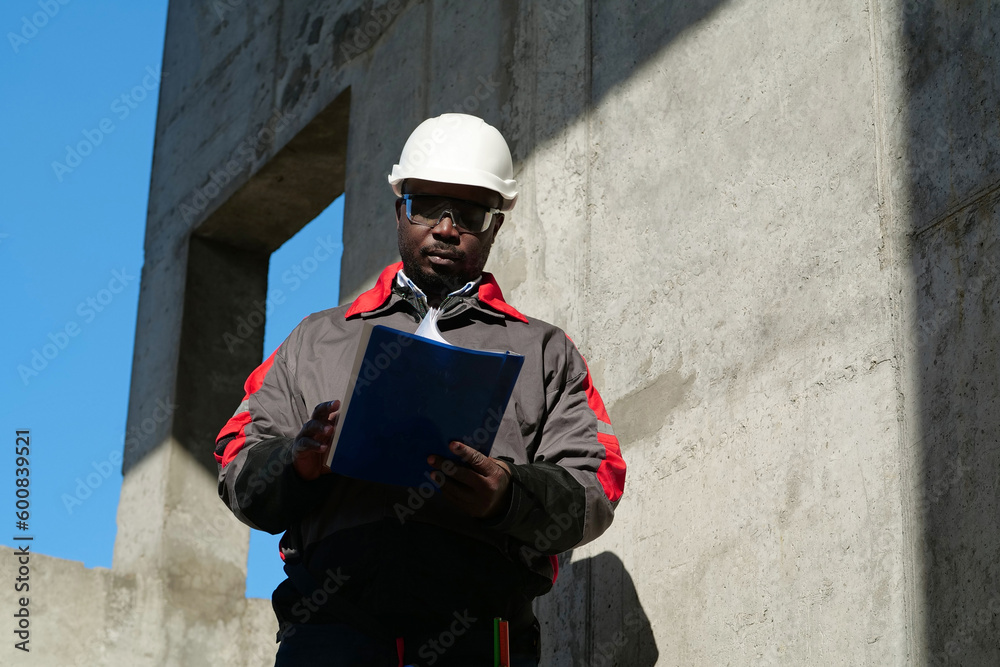 African american worker stands at construction site with work papers African american worker stands at construction site with work papers