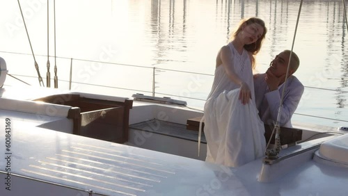 Couple in love young girl and guy spends time on yacht in sea. Summer, sea, early morning, sunrise, warm golden rays of sun. 4K Resolution