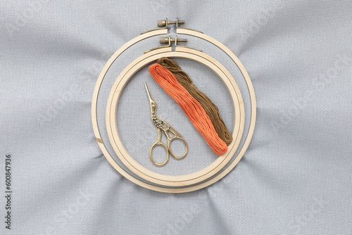 Flat lay top view photo of a mockup with an embroidery hoop. Wooden hoop for embroidery. Hobby concept. Grey blank canvas on wooden round frame as a background.