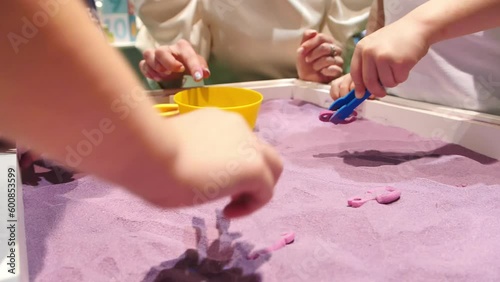 Child's hands playing with colorful magiс sand. Kids playing with sand and plastic toys. Sensory development and experiences, themed activities with children, fine motor skills development