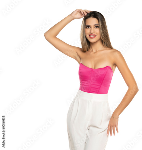young modern smiling woman in white pants and pink corset posing on white background