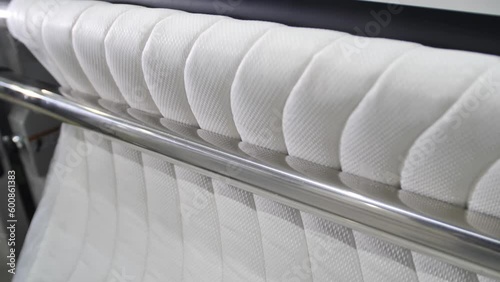 On modern machines manufactured upholstery fabric for furniture. On a large special equipment between the rollers lashed material for lining mattresses.