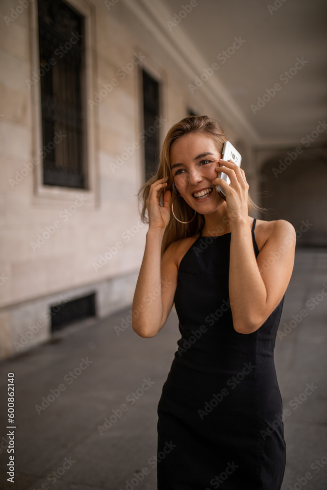 Pretty young woman using her mobile phone while walking through the city streets.