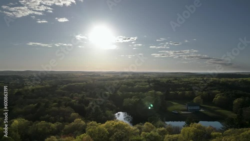 Sunset over wooded area with lakes and a house