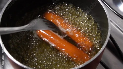 Garfo mexendo salsichas cozinhando na água fervente photo