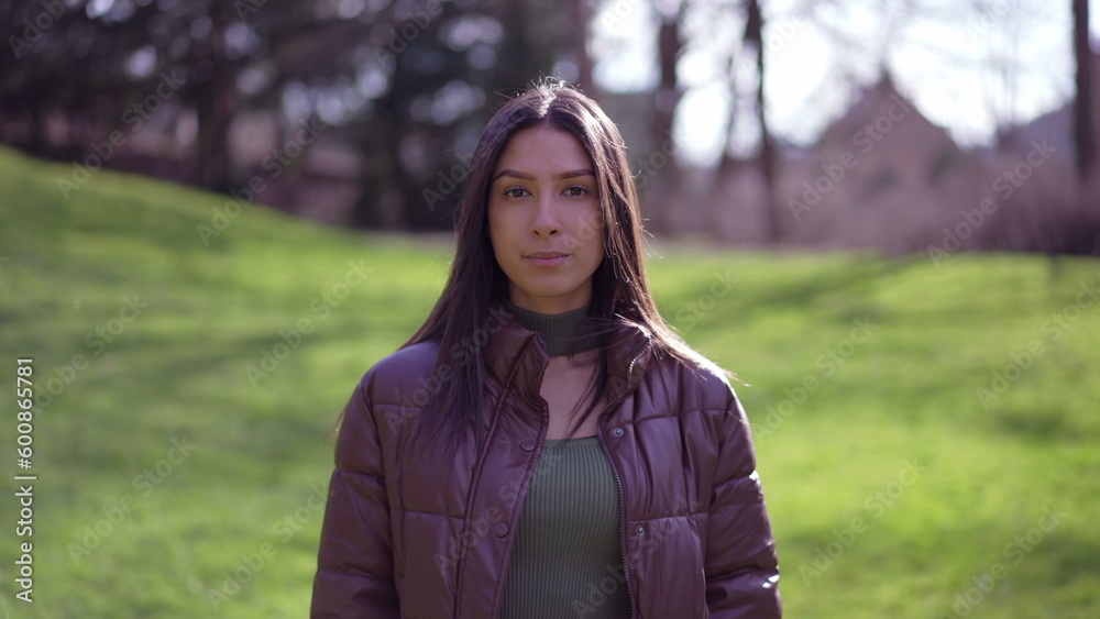 Portrait a young brunette adult girl standing outside at park looking at camera. Woman closeup face Portrait a young brunette adult girl standing outside at park looking at camera. Woman closeup face
