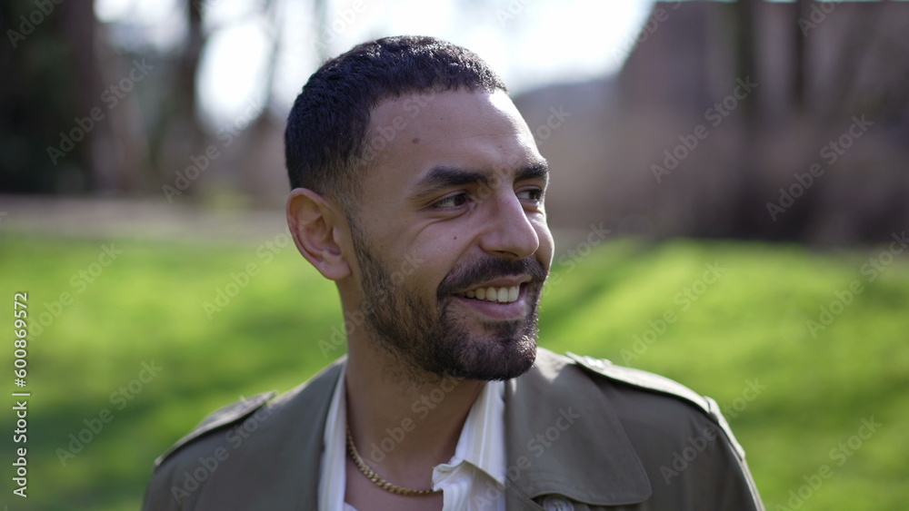 One happy Arab man closeup face walking forward toward camera smiling while at park during sunny day One happy Arab man closeup face walking forward toward camera smiling while at park during sunny day