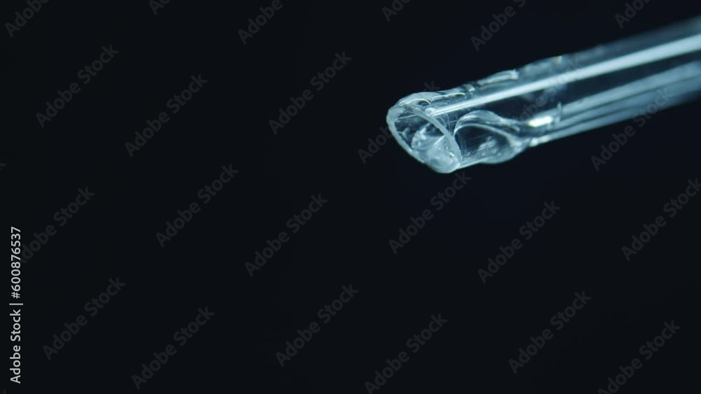 A glass pipette in close-up. Condensation dripping. Extract. Free space for text. Cosmetics. perfume, laboratory. On black background. Minimalism. A drop of water and gel. A glass pipette in close-up. Condensation dripping. Extract. Free space for text. Cosmetics. perfume, laboratory. On black background. Minimalism. A drop of water and gel.