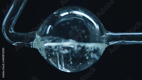 Boiling water in a spherical flask. Dark background. Laboratory equipment. Pharmacology and Medicine. Production of drugs. Extract preparation. Distillation or heating of liquids in a laboratory