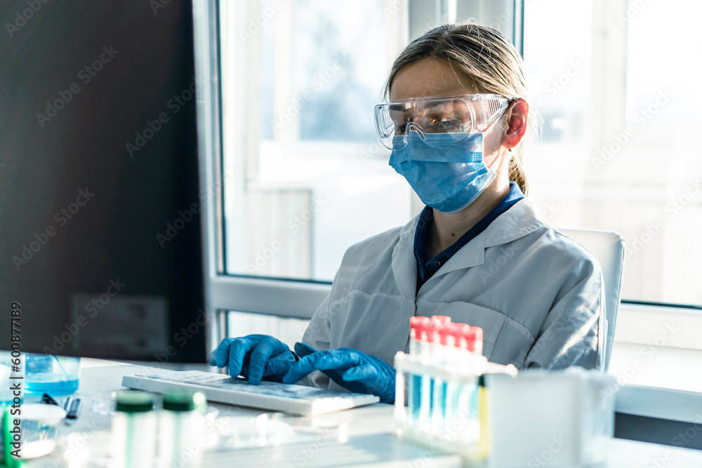 Doctor scientist in biological laboratory analyzes results research on his computer to find new cure. Chemist is engaged in the study of various chemicals in medical laboratory using computer program Doctor scientist in biological laboratory analyzes results research on his computer to find new cure. Chemist is engaged in the study of various chemicals in medical laboratory using computer program