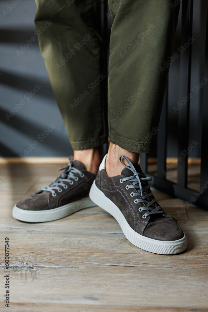 Close-up of male legs in pants and gray casual sneakers. Men's leather shoes. Collection of men's stylish summer shoes