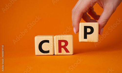 CRP - C-Reactive Protein Test symbol. Wooden cubes with word CRP. Doctor hand. Beautiful orange background. Medical and C-Reactive Protein Test concept. Copy space.