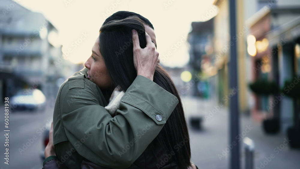 Fototapeta premium Young Arab man embracing woman standing in city street in empathy. Tracking shot of an affectionate compassionate couple. relationship support and gratefulness concept