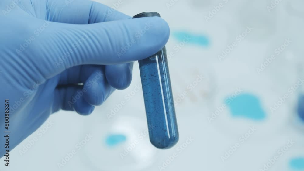 Test tubes blue liquid inside.In a laboratory, a scientist with a pipette analyzes a colored liquid to extract the DNA and molecules in the test tubes. Concept: research, biochemistry, nature, pharmac Test tubes blue liquid inside.In a laboratory, a scientist with a pipette analyzes a colored liquid to extract the DNA and molecules in the test tubes. Concept: research, biochemistry, nature, pharmac