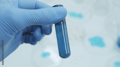 Test tubes blue liquid inside.In a laboratory, a scientist with a pipette analyzes a colored liquid to extract the DNA and molecules in the test tubes. Concept: research, biochemistry, nature, pharmac photo