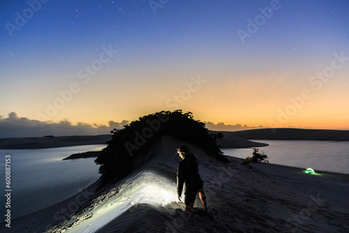 Homem com lanterna de cabeça observando o amanhecer em acampamento nos Lençóis Maranhenses photo