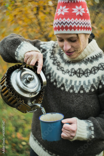 Woman pouring a tea from kettle outdoors in autumn nzture photo