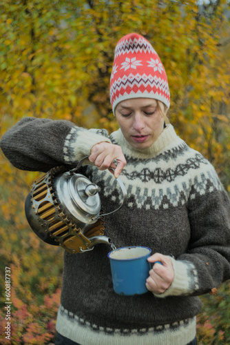 Woman pouring a tea from kettle outdoors in autumn nzture photo