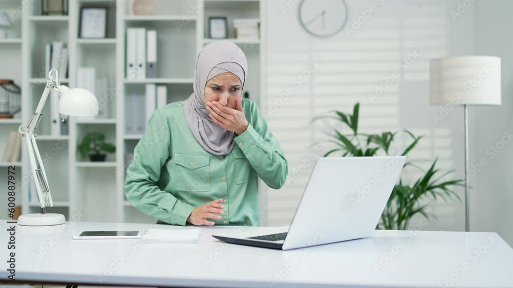 Muslim woman suffering from nauseous, wants to vomit while working on laptop while sitting at workplace in modern office. Sick arab employee in hijab has food poisoning and digestive problem indoor Muslim woman suffering from nauseous, wants to vomit while working on laptop while sitting at workplace in modern office. Sick arab employee in hijab has food poisoning and digestive problem indoor