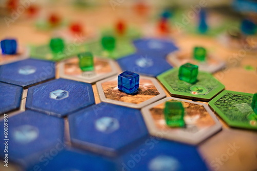 Żetony oraz elementy gry planszowej Terraformacja Marsa, widoczne niebieskie i brązowe płytki oraz niebieskie, zielone i czerwone kostki
