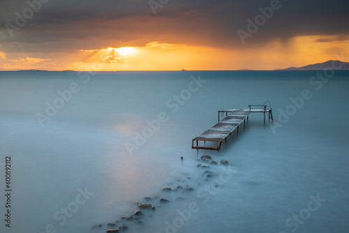 Wooden pier built into the sea and helping fishing  sunset colors and light
