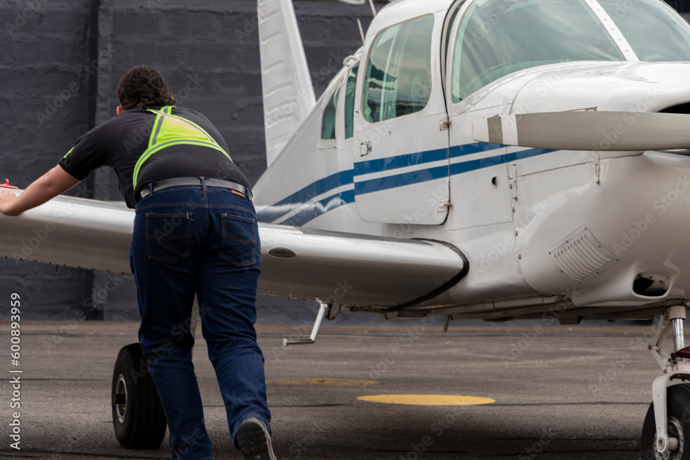 Young airport assistant moves small aircraft from the wing. Young airport assistant moves small aircraft from the wing.