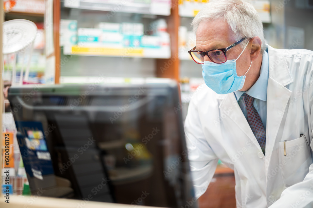 Pharmacist at work with a computer in his store Pharmacist at work with a computer in his store
